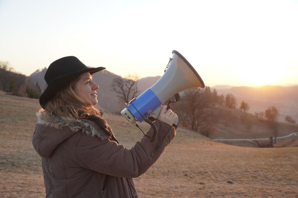 Person holding megaphone in nature mimicing golden jackal howling