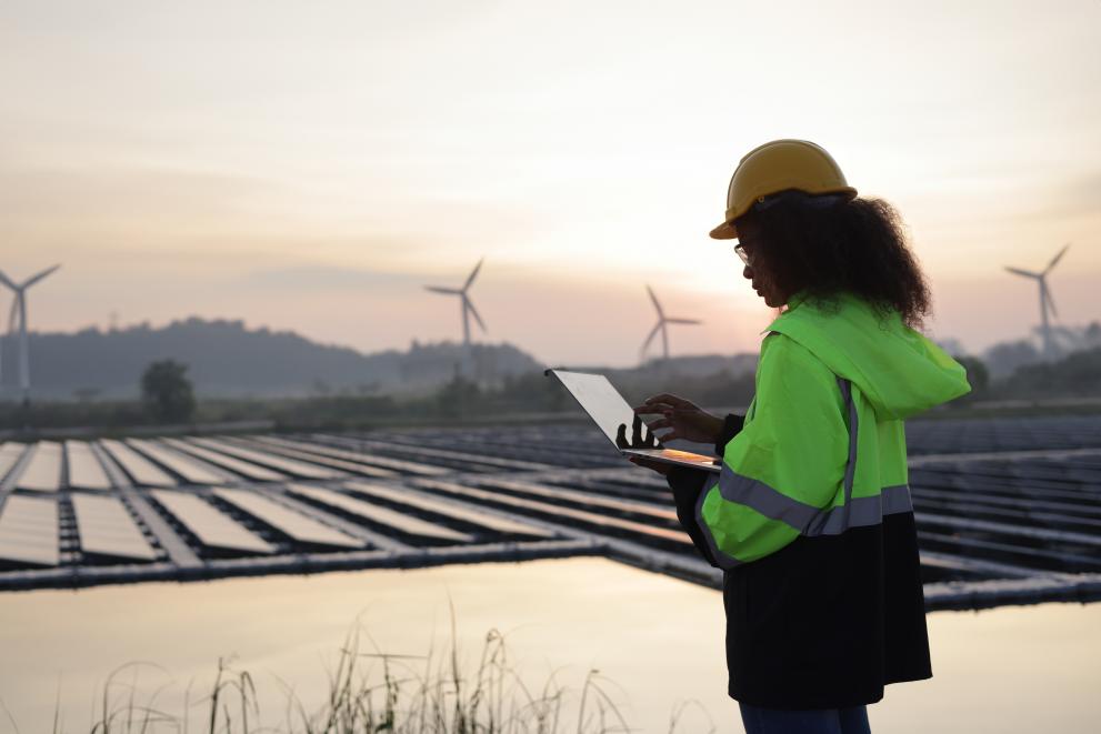 A female worker uses a laptop at site of a floating solar and wind turbine fame